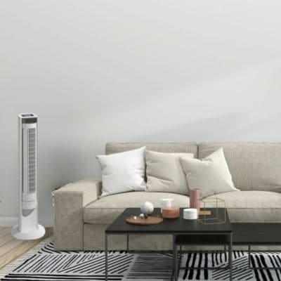 Ventilateur colonne blanc élancé près d’un canapé beige dans un salon, table basse et accessoires sur un tapis noir et blanc. Comment choisir ventilateur colonne.